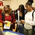 学生们在黑人大学博览会的展台上阅读和收听更多信息
